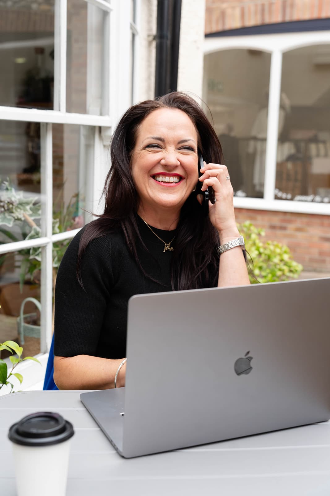Danielle Sands smiling on the phone beside her laptop
